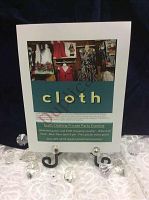 Promotional sign mounted on board displayed on metal easel surrounded by clear acrylic gems