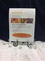 Gift certificate printed on white paper with 4Cats Arts Studio logo, party details and orange oval indicating gift value, displayed on a black decorative easel atop a lace tablecloth.