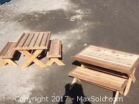 Two small cedar picnic tables on pavement
