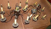 Chandeliers laid out on sofa showing candle-like electric holders and metal arms with wooden components