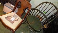 Two reproduction chairs side by side on floor; a green Windsor chair and a brown side chair with fabric seat cushion