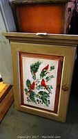 Closed hand painted wooden cabinet featuring red cardinal birds on leaves hand painted on door panel.