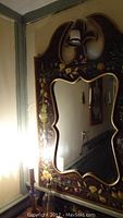 Upper section of mirror showing floral and fruit decorations.