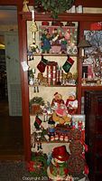 Full view of shelves with assorted Christmas decorations including figurines, stockings, candles, and plush toys