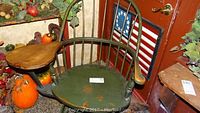 Full view of the reproduction Windsor desk chair showing green spindle backrest and attached wooden writing surface on the right armrest with pumpkins and fall decor in the background.