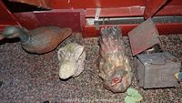 Cast iron duck, garden rabbit, garden rooster, and the two birdhouses arranged on carpet near a red wall.