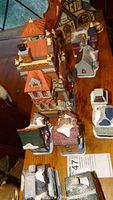 Overhead shot showing multiple ceramic Christmas houses with varying roof colors and partial snow effects, emphasizing size variation from tallest to smallest