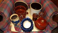 Set of ceramic kitchenware items consisting of cheese crocks, bean pot with lid, small container, and blue flower pot placed on a chair for display.
