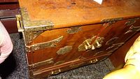 Close-up of top surface showing scratches and detailed brass corner protector and latch hardware on the cabinet door.