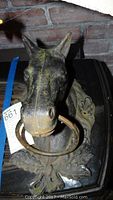 Front view of antique cast iron horse hitch showing the horse head with ring in mouth and detailed floral base