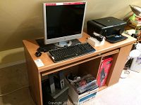 Photo showing the wooden desk with HP monitor, printer, keyboards, and speaker boxes on shelves.