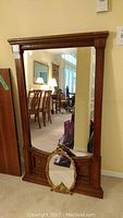 Full view of the large oak wood framed wall mirror with the small gold standing mirror positioned in front of it showing scale and relative size.
