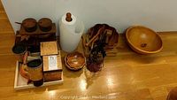Photo showing wood condiment holder with glass containers on tray, copper kettle, wood salad bowl with servers, smaller wooden bowls, and metal wine bottle carrier.