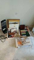 Overview of the lot including Verilux lamp, boxes with games and art items.
