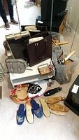 Wide view showing white shoe stand with various bags, slippers, hangers, and accessories placed on and around it.