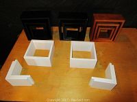 Top view of shadow boxes in black, white, and wood-tone colors arranged on a wooden surface