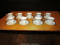 Nine Royal Doulton cups and saucers arranged in two rows on a wooden surface, showing the full set of 18 pieces.