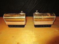 Photo showing both brass canister shoe shine brushes side by side from above on wooden surface.
