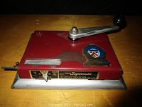Top view of the red metal Supermatic cigarette machine with visible handle, badge, and front nameplate.