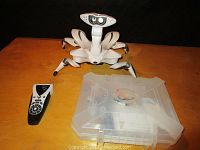 Front view of the white Wowwee robot with remote and plastic case containing helicopter toy