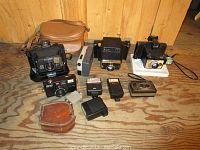 Overview of vintage cameras and accessories on wooden floor.
