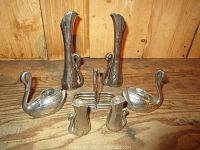 Image showing the full silver plated swan set arranged on a wooden surface, including vases, creamers, toast rack, and salt and pepper shakers.