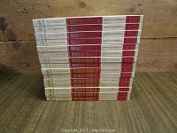 Stacked spines of multiple World War II illustrated encyclopedia volumes in red, white, and gold colors.