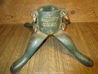 Front view of the cast iron Christmas tree stand showing "A MERRY XMAS" embossed text and three legs