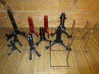 Front perspective of 10 small plate holders in black, red, and gold-tone metal on wooden surface with wood wall background