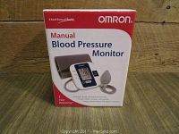 Front view of Omron Manual Blood Pressure Monitor boxed, showing product image and one year warranty.