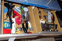 Drawer full of various kitchen utensils and tools including a Pampered Chef chopper and measuring spoons