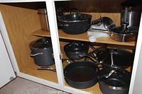 Wooden cabinet shelf with non-stick pots and pans on two levels