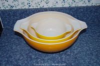 Three yellow and white Pyrex bowls stacked together showing size difference.