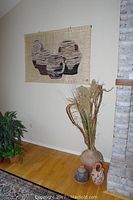 Photo showing tapestry on wall, below a 17 inch vase with dried flowers, two pottery items on the floor—a 13.5 inch wedding pot and another signed vase.