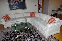 Full view of the three-piece sectional sofa with striped upholstery and three striped throw pillows in red-orange tones.