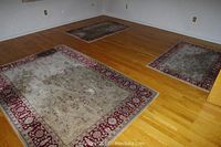 Three wool area rugs arranged on hardwood floor showing soiling and wear; one large (5x7) and two smaller (2.5x3.5) rugs visible