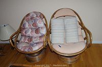 Two rattan swivel chairs side-by-side on a hardwood floor, both with cushions in different styles.
