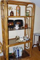 Wooden shelving unit with glass shelves holding various decor items including pottery, wood trays, glass, and books