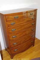 Full front view of bow-front dresser showing six drawers and bracket feet