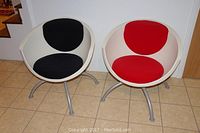 Two Gubbo chairs side by side on tiled floor near stairs. One has red cushions, the other black.
