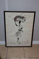 The framed artwork showing the full piece of a woman carrying basket on head in watercolor and ink.