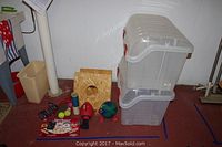 Photo showing the collection of items arranged on the floor including storage bins, bean bag toss board, ball mitt, balls, hand weights, and card decks.