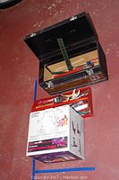 Open black metal Craftsman toolbox showing various hand tools inside including wrenches, screwdrivers, pliers, and hammer. Craftsman Buffer/Polisher System in original boxed packaging on floor beside toolbox.