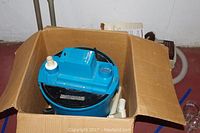 Blue Craftsman Home N Shop Vac inside a cardboard box with hose attachments.