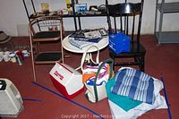 Lot items grouped: step stool, chairs, table, coolers, cushions, bag, towels, and books.