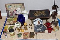 Wood stool, decorative plaques, blue glass vase, paperweights, and assorted decor items arranged on a tile floor.