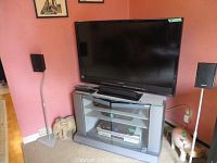 Wide shot of Sony TV on stand with remote and two speaker stands