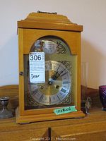 Single chime wind-up clock with natural wooden case and decorative clock face close-up