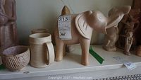 Photo showing stoneware items including elephant figurine and mugs on shelf