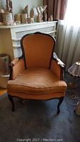 Front view of orange velvet upholstered occasional chair showing overall condition and style.